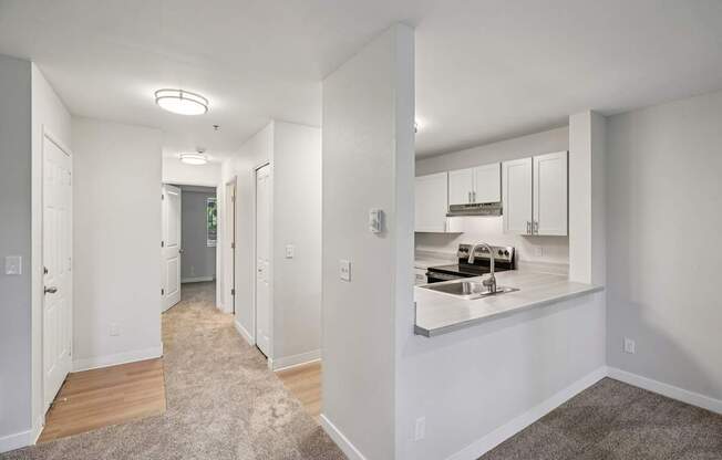 A hallway with a kitchen visible in the mirror.
