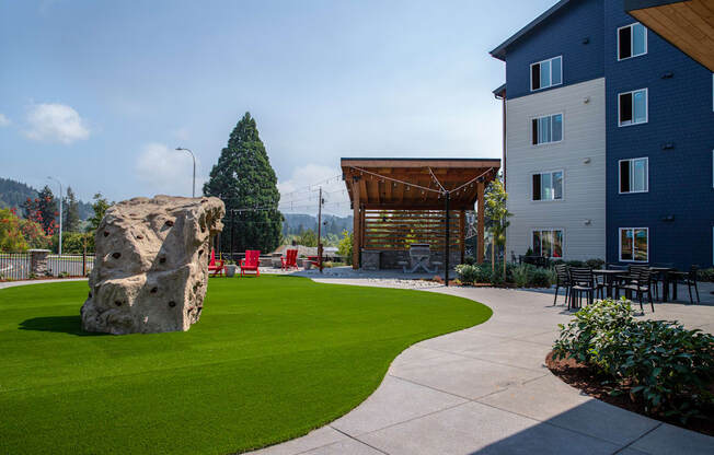 a large rock sits in the middle of a grassy area with a building in the backgroundat Scouter's Mountain, Happy Valley, OR