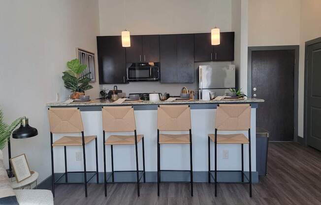 A kitchen with black cabinets and a bar area with four chairs.