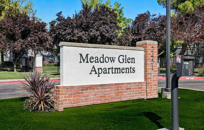 A sign that says Meadow Glen Apartments in front of a building.