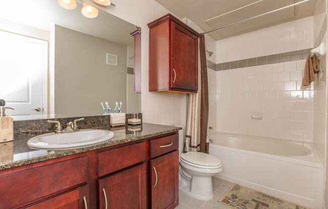 A bathroom with a white tub and a brown vanity.