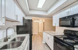 A kitchen with black appliances and white cabinets.