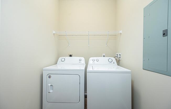 a washer and dryer in a room with a white wall and a closet