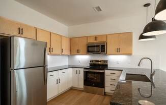 A kitchen with wooden cabinets and a stainless steel refrigerator.