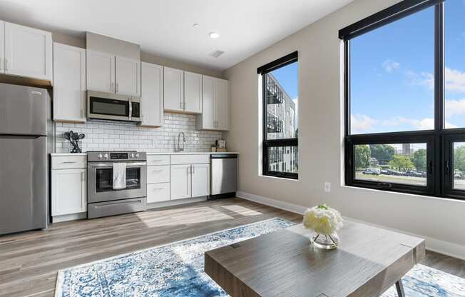 a kitchen with white cabinets and stainless steel appliances and a wooden table with a vase of