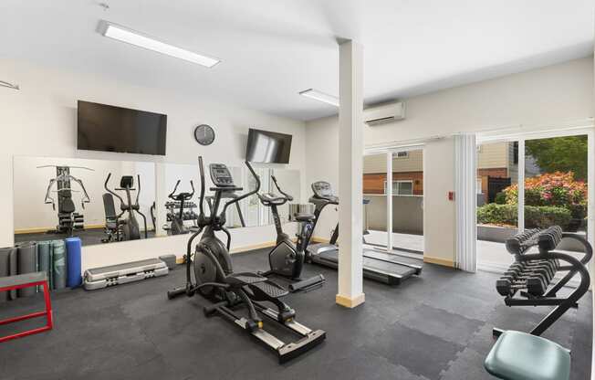 a gym with cardio equipment and a flat screen tv at Guinevere Apartment Homes, Washington