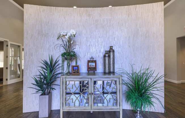 a living room with plants and a glass cabinet