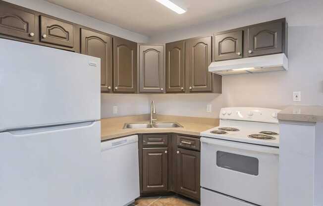 A kitchen with brown cabinets and white appliances.