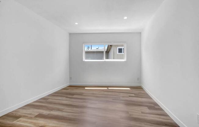 a room with white walls and a window and wooden floors