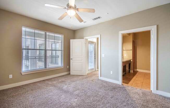 a bedroom with a ceiling fan and a door leading to a bathroom At Metropolitan Apartments in Little Rock, AR