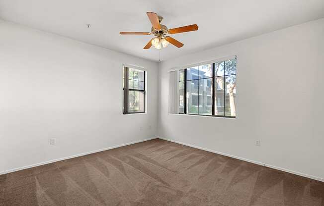 A room with a ceiling fan and carpeted floor.