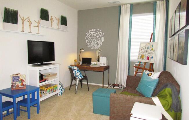 a living room with a couch and a desk and a tv at The Vines at Riverpark, LLC, Oxnard