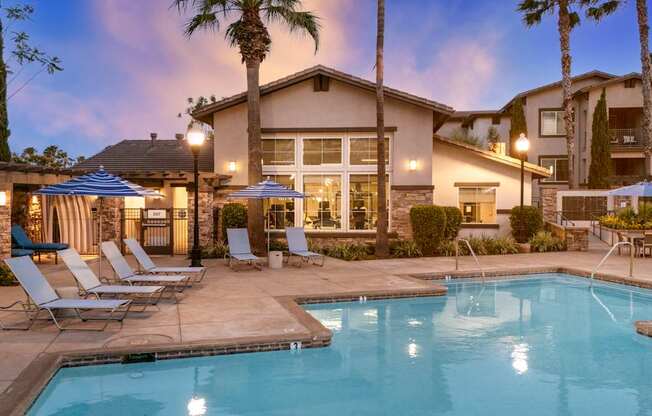 A pool surrounded by lounge chairs and umbrellas.