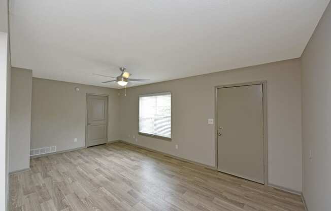 an empty living room with a ceiling fan