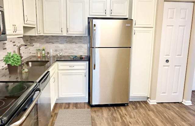 a kitchen with a stainless steel refrigerator and white cabinets