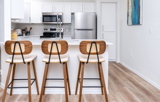 a kitchen with wooden bar stools in front of a counter with a kitchen island