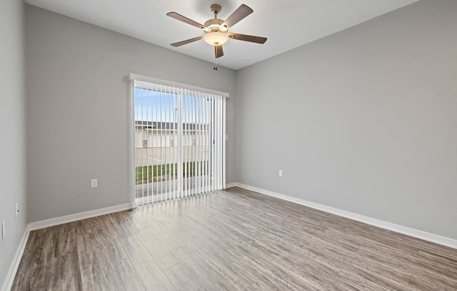 an empty living room with a ceiling fan and a window