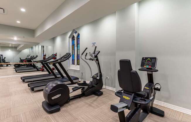 A gym with treadmills, exercise bikes, and dumbbells.