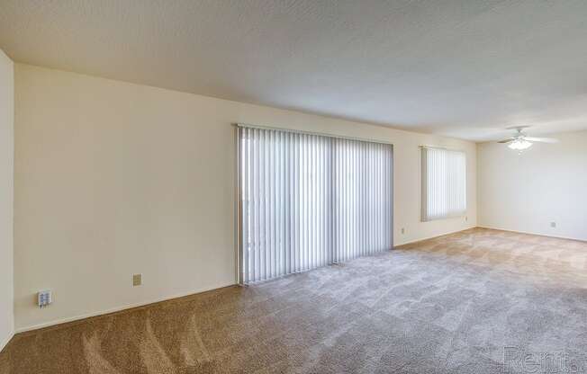 an empty living room with a sliding glass door and a ceiling fan at Terrace View Apartments, Daly City California