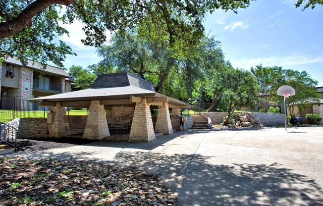 a stone gazebo with a basketball hoop in a courtyard