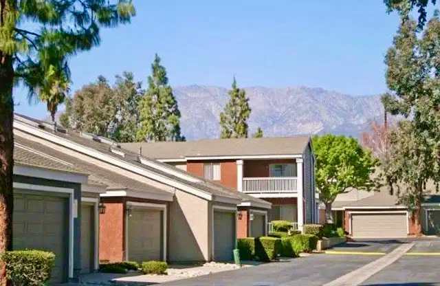 A row of townhouses with garages and trees with a mountain view.