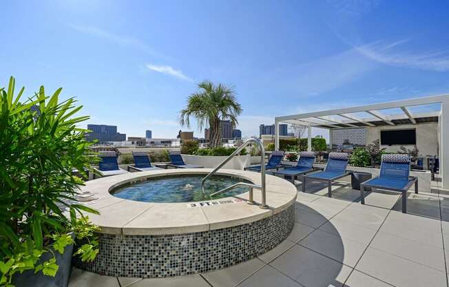 Rooftop pool with a hot tub with blue chairs and a white awning at Dominion Post Oak apartments in Houston, TX