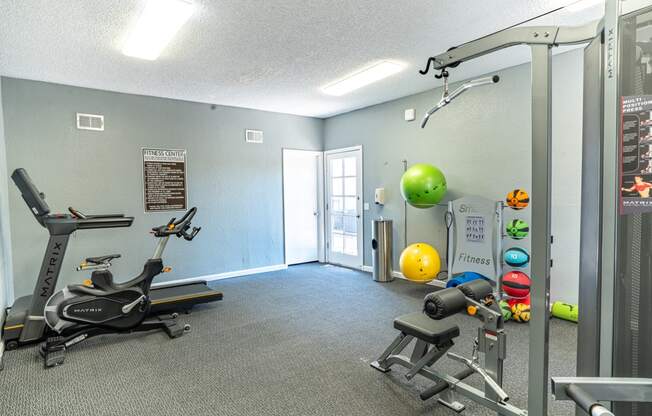 a gym with exercise equipment and a yellow ball on the wall