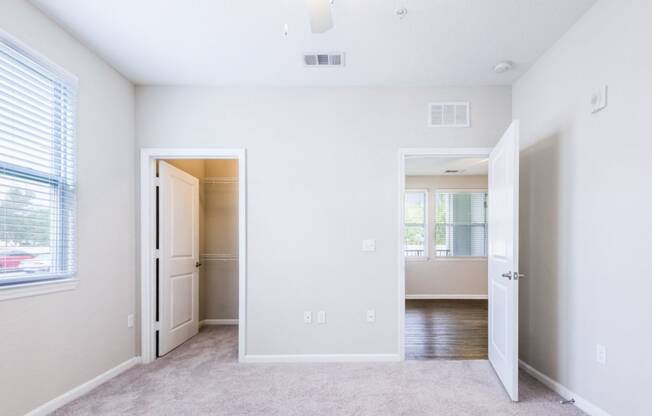 an empty bedroom with a door to a hallway and a closet