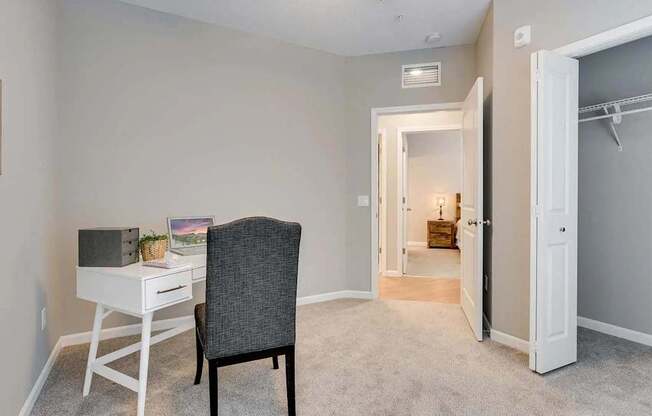 a bedroom with a desk with a chair and a door to a bathroom.  Circle Pines, MN Lexington Lofts