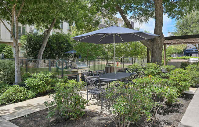 A patio with a table and chairs under an umbrella.