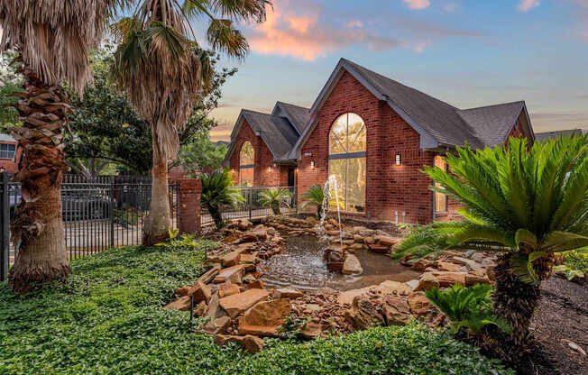 A house with a red brick exterior and a waterfall in the front yard.