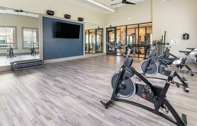 a gym with cardio equipment and a flat screen tv