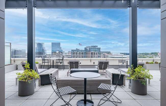 A patio with a table and chairs overlooking a city skyline.