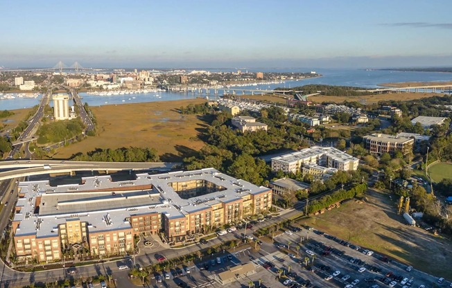 A large building complex is surrounded by a parking lot and a body of water.