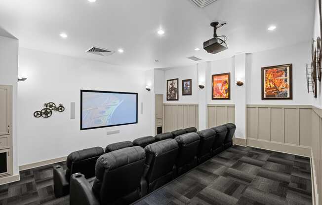 a theater room with a row of black chairs and a tv on the wall