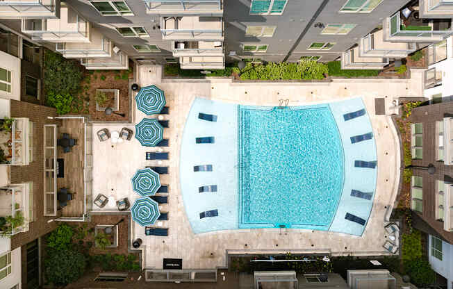 A swimming pool surrounded by a patio with chairs and umbrellas.