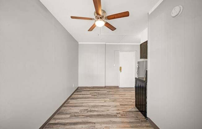 a living room with white walls and a ceiling fan