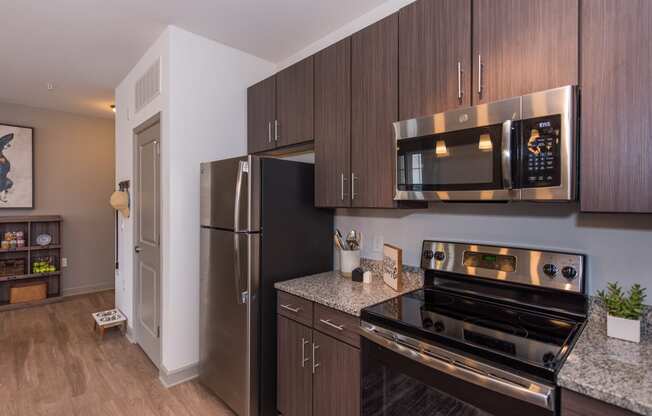 a kitchen with dark wood cabinets and stainless steel appliances at The Whitworth, Williamsburg, VA