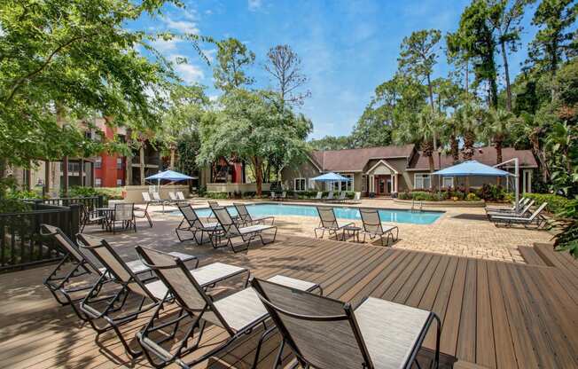 a swimming pool with chairs and tables on a wooden deck