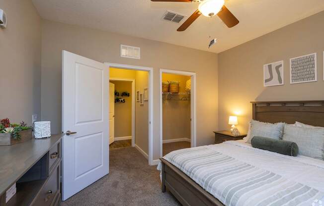 A bedroom with a bed, dresser, and ceiling fan.