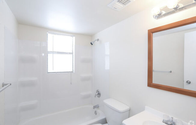A white bathroom with a toilet, sink, and bathtub.