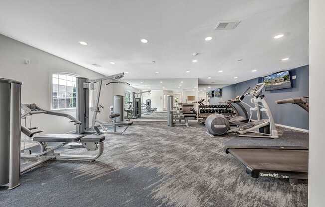 A spacious gym with a variety of equipment including treadmills, stationary bikes, and weight machines.