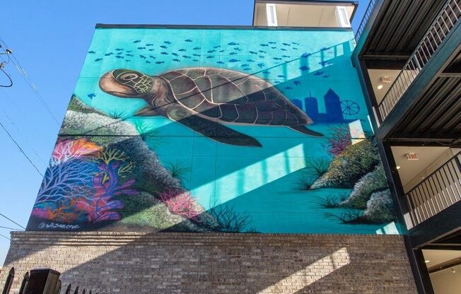 Large wall with painting of large turtle swimming.