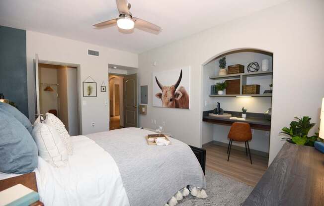 A bedroom with a bed, desk, and a painting of a bull on the wall.