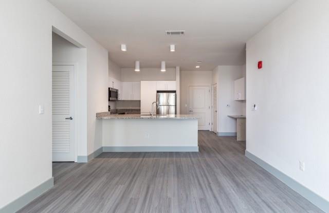 Lengthwise view from the living room leading to the kitchen with hardwood style flooring and modern lights at Lofts at South Lake, Clermont, FL