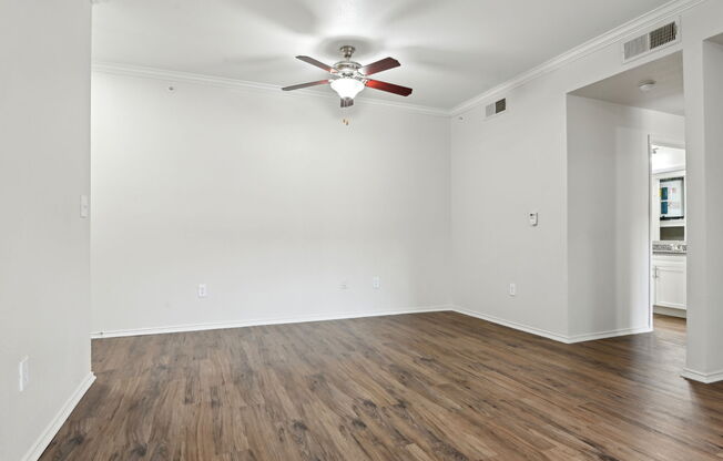 A room with a ceiling fan and wooden flooring.