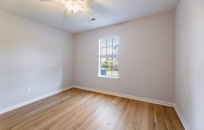 Empty room with a window and wooden floor.