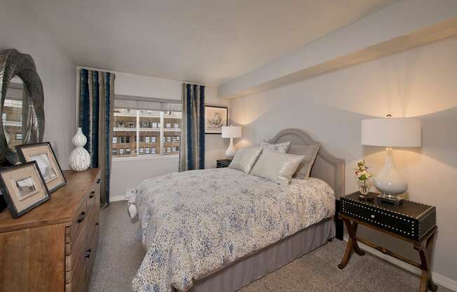 A bedroom with a bed, nightstand, and a dresser with a mirror.