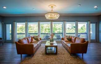 A living room with brown leather couches and a chandelier.