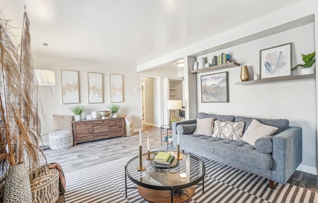 A living room with a grey couch and a glass coffee table.